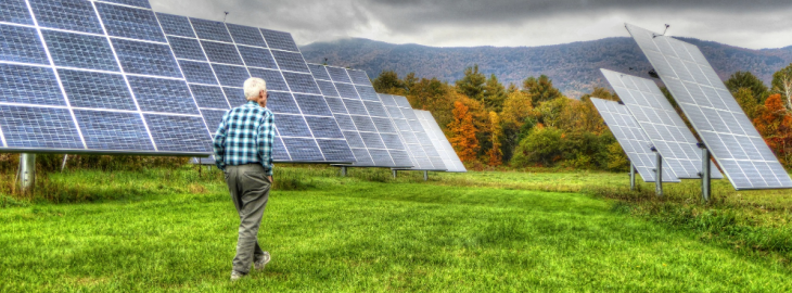 starszy człowiek idący wzdłuż rzędu paneli słonecznych